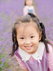 Little baby in a lavender field and smiling at camera, beautiful young girl with lovely braid.