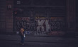 Woman walking near graffiti wall on dark street