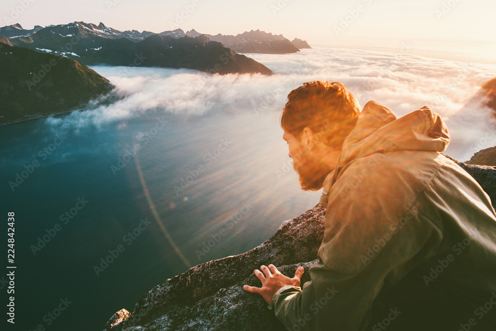 Man on the edge cliff above sea gaze into abyss lying down traveling in mountains adventure lifestyle extreme vacations - obrazy, fototapety, plakaty 
