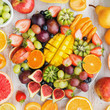 Variety of cut fruits and berries platter, strawberries blueberries, mango orange, apple, grapes, kiwis on the white wood background, copy space for text, square, top view, selective focus