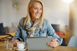 © goodluz - Woman at coffee shop websurfing on digital tablet