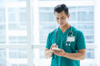 © DragonImages - Smiling handsome Asian doctor reading text message in his smartphone