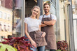 © LIGHTFIELD STUDIOS - smiling male and female florists standing near flower shop and looking at camera