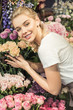 © LIGHTFIELD STUDIOS - smiling attractive florist hugging bouquets in flower shop and looking at camera
