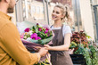 © LIGHTFIELD STUDIOS - smiling florist giving beautiful bouquet of chrysanthemums to customer near flower shop