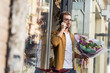 © LIGHTFIELD STUDIOS - handsome man going out from flower shop with bouquet and talking by smartphone