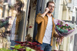 © LIGHTFIELD STUDIOS - handsome man going out from flower shop with bouquet of flowers and talking by smartphone