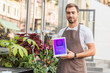 © LIGHTFIELD STUDIOS - handsome florist holding tablet with shopping appliance near flower shop