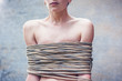 © olezzo - Beautiful stylish young woman with a short haircut tied in a rough rope, women's rights, the problem of family violence concept