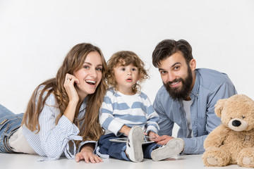 Smiling family sitting together at white studio and watching their favorite cartoons on laptop.