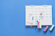 close up of pin on calendar on the blue table background, planning for business meeting or travel planning concept