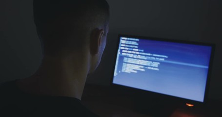 IT Programmer man typing in program code. Developer at work overtime. Hacker hacking late at night.