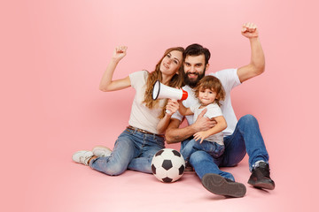 Wall Mural - The happy father, mother and son playing together with soccer ball on pink studio background