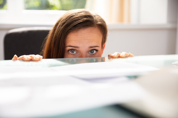 Businesswoman Peeking Behind The Desk