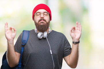 Sticker - Young hipster man wearing red wool cap and backpack over isolated background relax and smiling with eyes closed doing meditation gesture with fingers. Yoga concept.