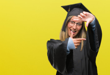 Poster - Young beautiful woman wearing graduated uniform over isolated background smiling making frame with hands and fingers with happy face. Creativity and photography concept.