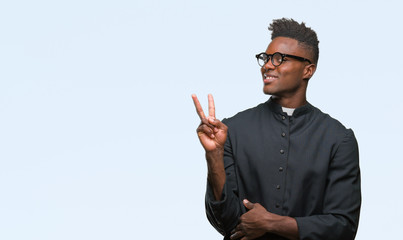 Sticker - Young african american priest man over isolated background smiling with happy face winking at the camera doing victory sign. Number two.