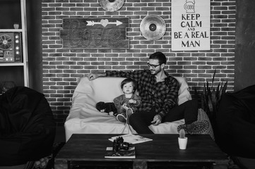 happy man and his arms embrace his son. Family mod on the sofa at home. White shirt. Father's Day