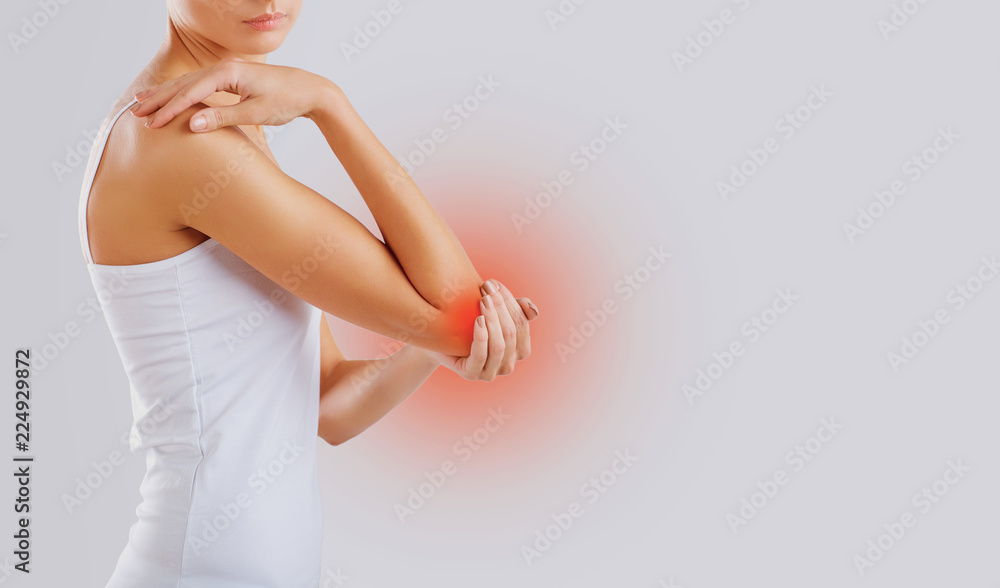 Pain, injury in the elbow joint. A woman holds her hand to her elbow. - obrazy, fototapety, plakaty 