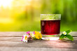 Glass Of Berry Juice With Meadow Flower On An Old Wooden Table On Bright Sunny Day Or At Dawn. Cranberry, Cherry, Raspberry Or Grape Cold Juice In Misted And Covered With Drops Of Water Glass Cup.