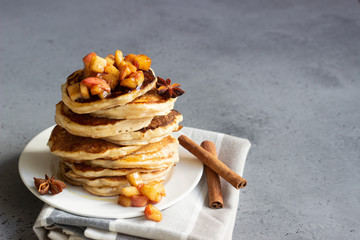 Poster - Stack of delicious sweet and spicy apple pancakes with fried caramelized apples, anise, cinnamon and honey on a white plate. Autumn breakfast. Copy space.