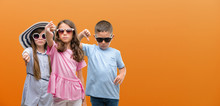 Group Of Boy And Girls Kids Over Orange Background With Angry Face, Negative Sign Showing Dislike With Thumbs Down, Rejection Concept