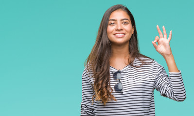 Canvas Print - Young beautiful arab woman wearing sunglasses over isolated background smiling positive doing ok sign with hand and fingers. Successful expression.