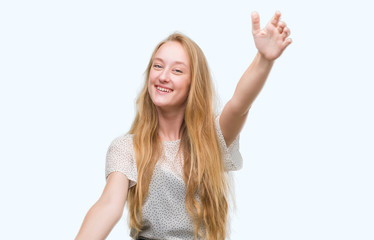 Wall Mural - Blonde teenager woman wearing moles shirt looking at the camera smiling with open arms for hug. Cheerful expression embracing happiness.