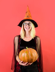 Wall Mural - Halloween party. Happy woman in witch costume with magic Pumpkin celebrating Halloween. Beautiful girl in witches hat. Magical witch girl in hat holds pumpkin. Witch hat. Jack-o-lantern. Funny Pumpkin