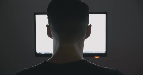 Back view of young man surfing internet at night