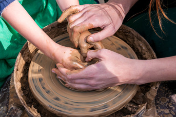 Pottery training, four hands make a pot of clay