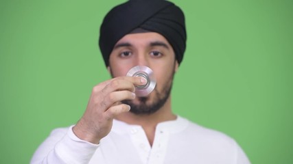 Sticker - Young handsome bearded Indian man playing with fidget spinner