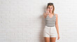 © Krakenimages.com - Young beautiful blonde woman over white brick wall doing stop sing with palm of the hand. Warning expression with negative and serious gesture on the face.