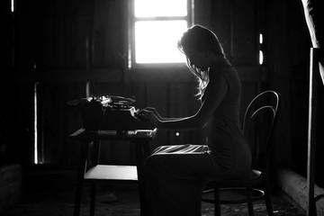 A girl prints on an old typewriter