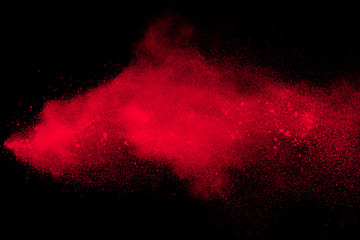 Red color powder explosion on black background.Freeze motion of red dust particles splashing.