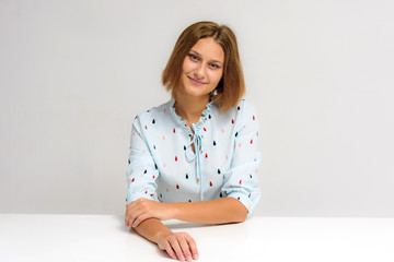 Portrait of a young beautiful girl on a white background at the table.