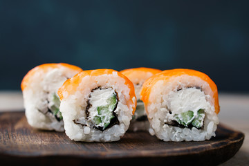 Japanese cuisine, food background. Tasty appetizing sushi rolls with salmon served on wooden plate, copy space