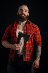 Wall Mural - bearded mohawk male holding axe on chest and posing in studio