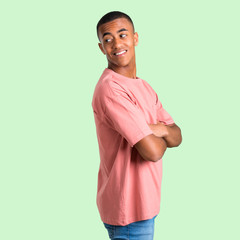 Dark skinned man in lateral position while looking over the shoulder with a smile on green isolated background