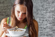 © pavel siamionov - portrait of young teenager brunette girl with long hair eating muesli on gray wall background
