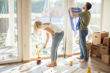 Young couple working, clining in new apartment with big window wall