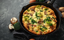 Homemade Frittata With Mushrooms, Broccoli, Feta Cheese, Green Peas And Bacon On Cast Iron Skillet