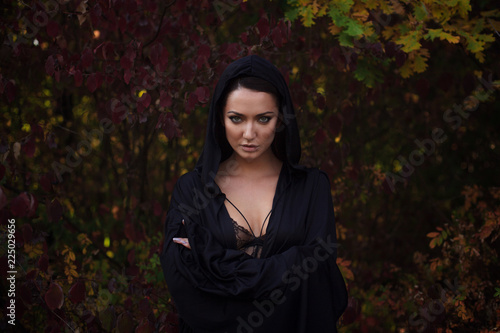 Fotomural Young woman in the black cloak in the autumn forest
