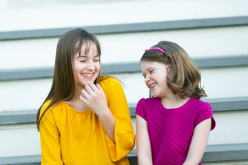 Wall Mural - Sisters Sitting on Outdoor House Stairs Laughing and Telling Secrets