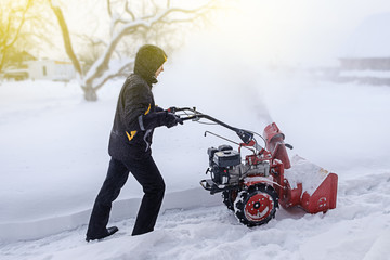 young man removes snow with a snowplower