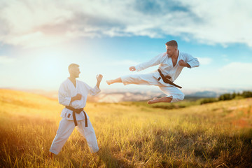 Wall Mural - Karate fighters, kick in flight on training fight