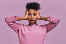 Stunned African American Female Stares At Camera And Keeps Mouth Opened, Scratches Head And Looks Surprisingly, Realizes Bad News, Stands Against Lavender Background. People, Reaction, Ethnicity