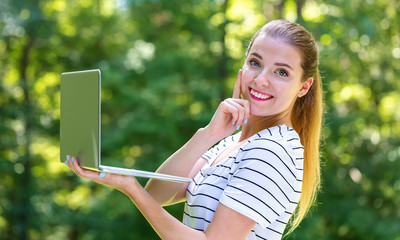 Wall Mural - Young woman with a laptop computer on a bright summer day in the forest