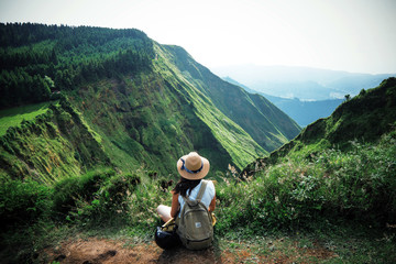 woman traveler holding hat and looking at amazing mountains and forest, wanderlust travel concept, s