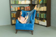 © satura_ - People, education and technology concept - Woman reading digital tablet in armchair in library